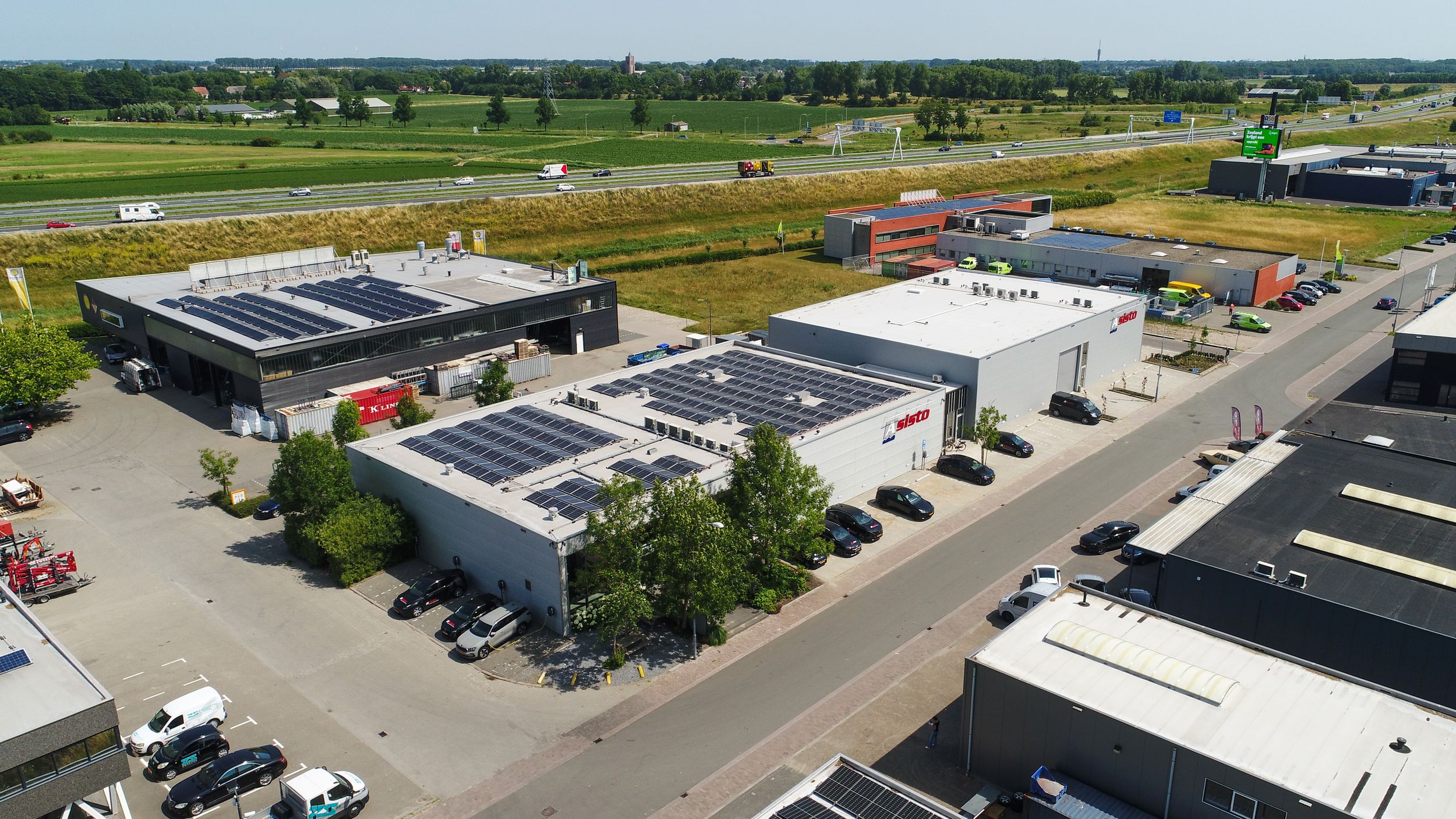 Aerial view of industrial complex with solar panels and parking lots.