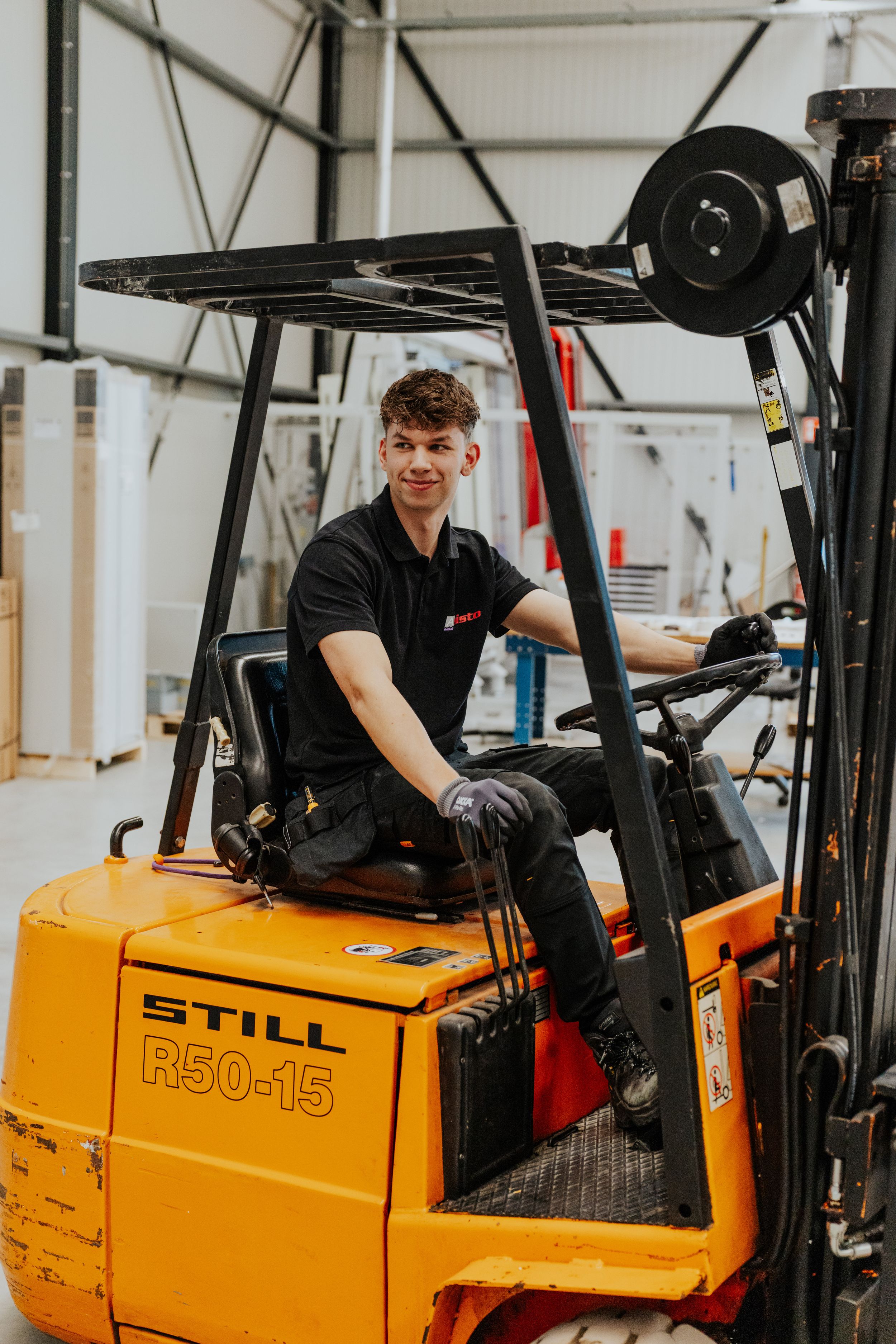 Worker operating yellow STILL forklift in warehouse setting.
