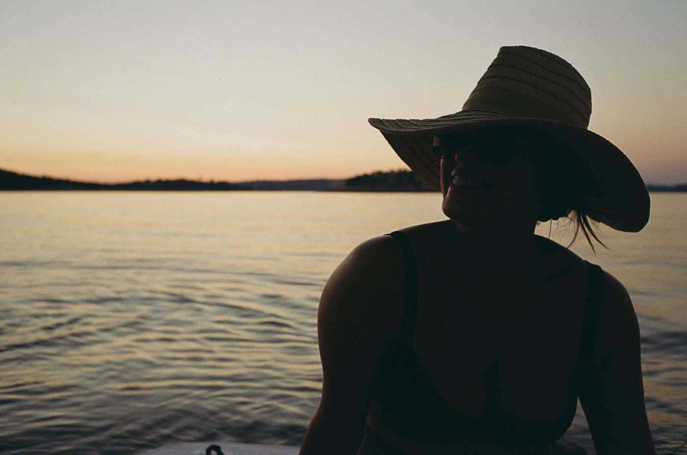 Scenic sunset at sea with a silhouetted person on a boat enjoying the calming orange-lit ocean waters.
