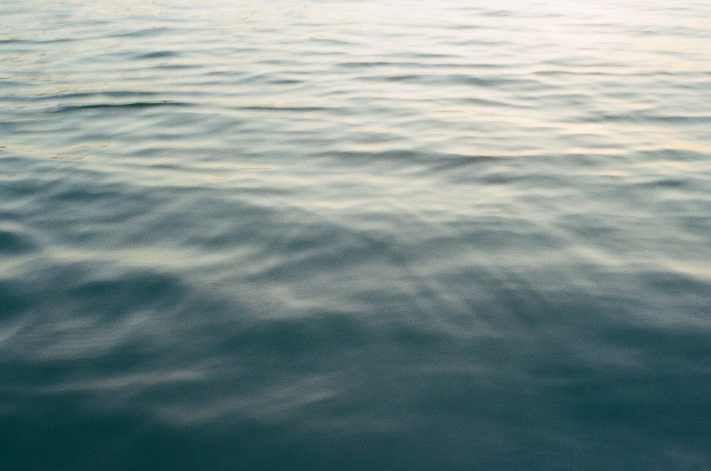 Aerial view of rippling ocean waves reflecting sunlight during a calm day at sea.