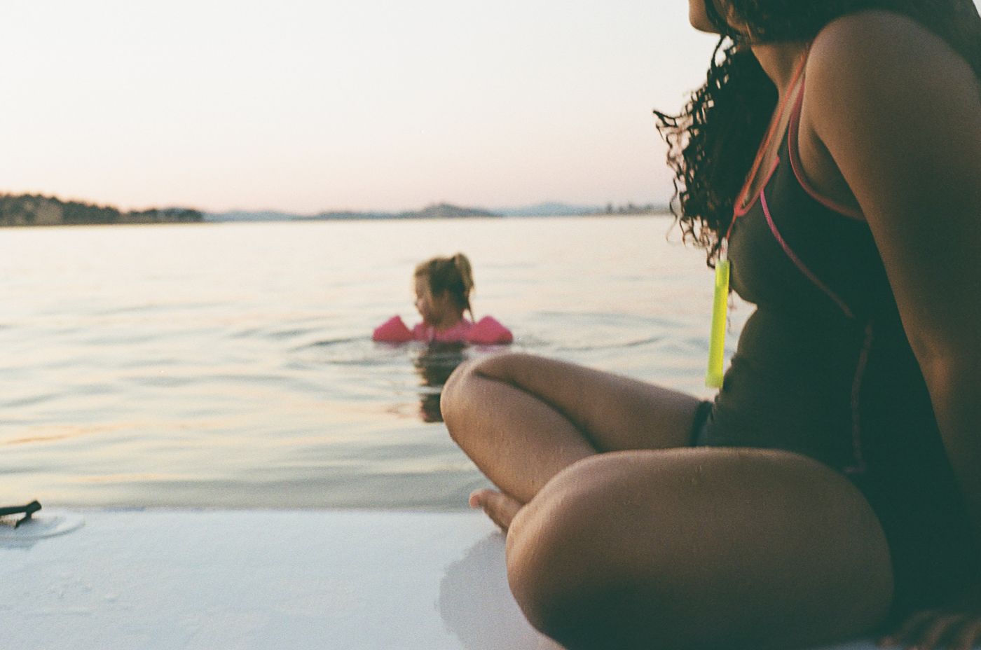 A person relaxes on a boat while looking out at the tranquil ocean waters at sunset.