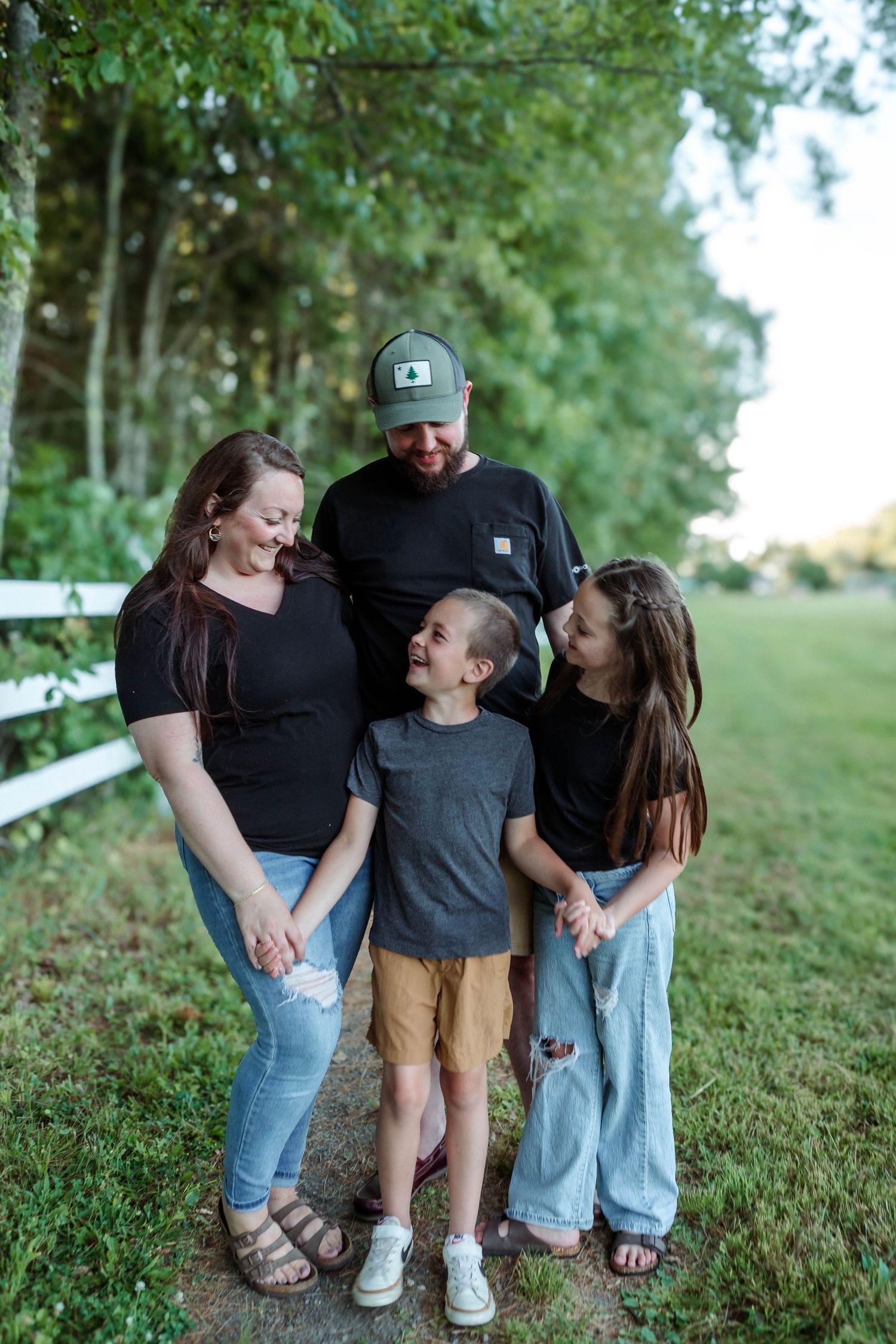 Family group wearing casual clothing shares candid moments together on a grassy hillside.