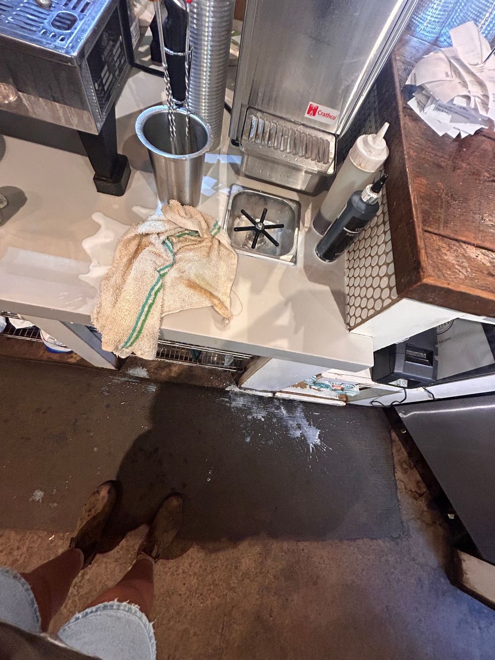 Equipment and supplies scattered on a stainless steel restaurant kitchen counter with food service items visible.