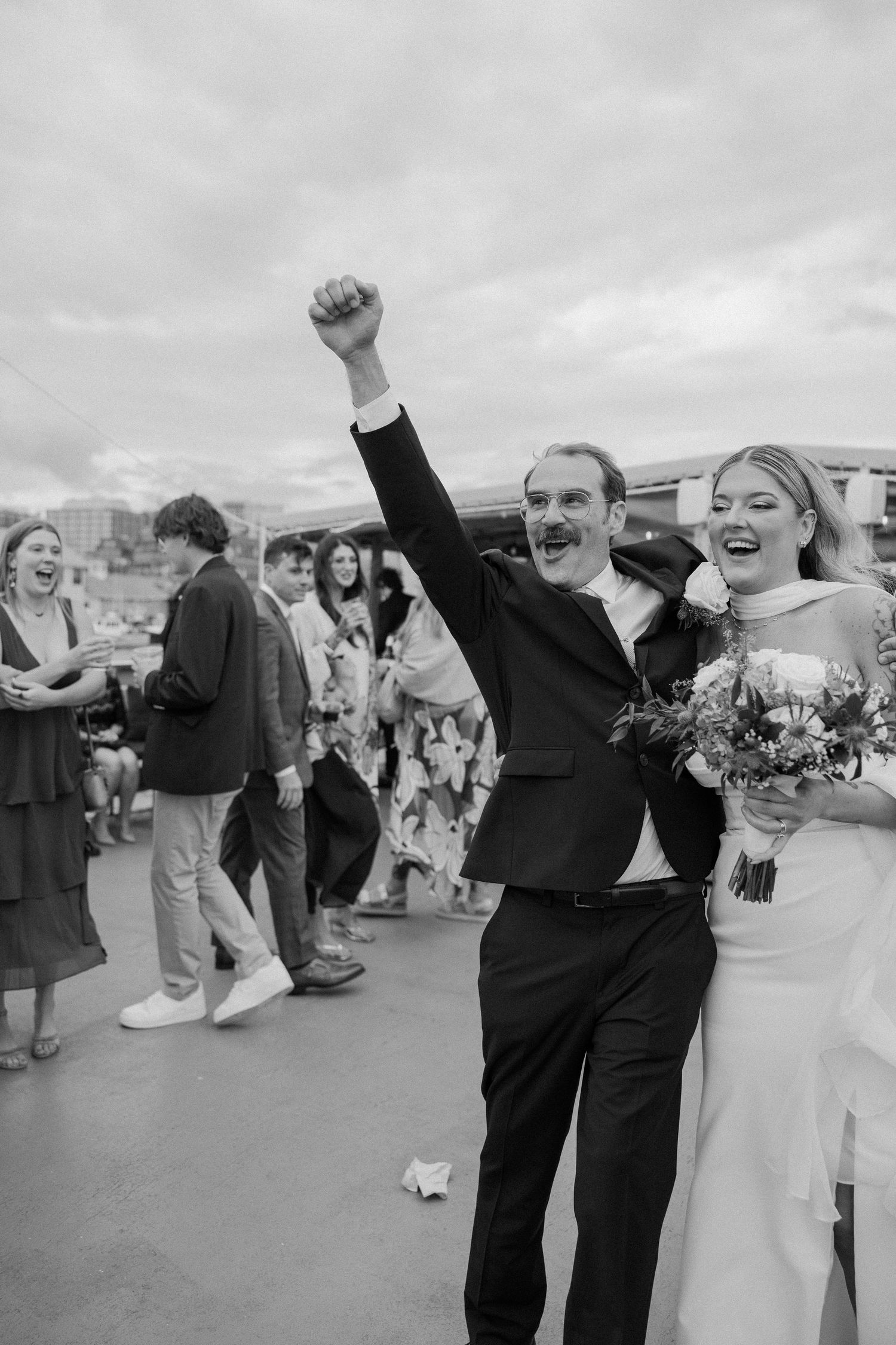 Joyful celebration sequence showing a couple raising their arms in excitement at an outdoor wedding.