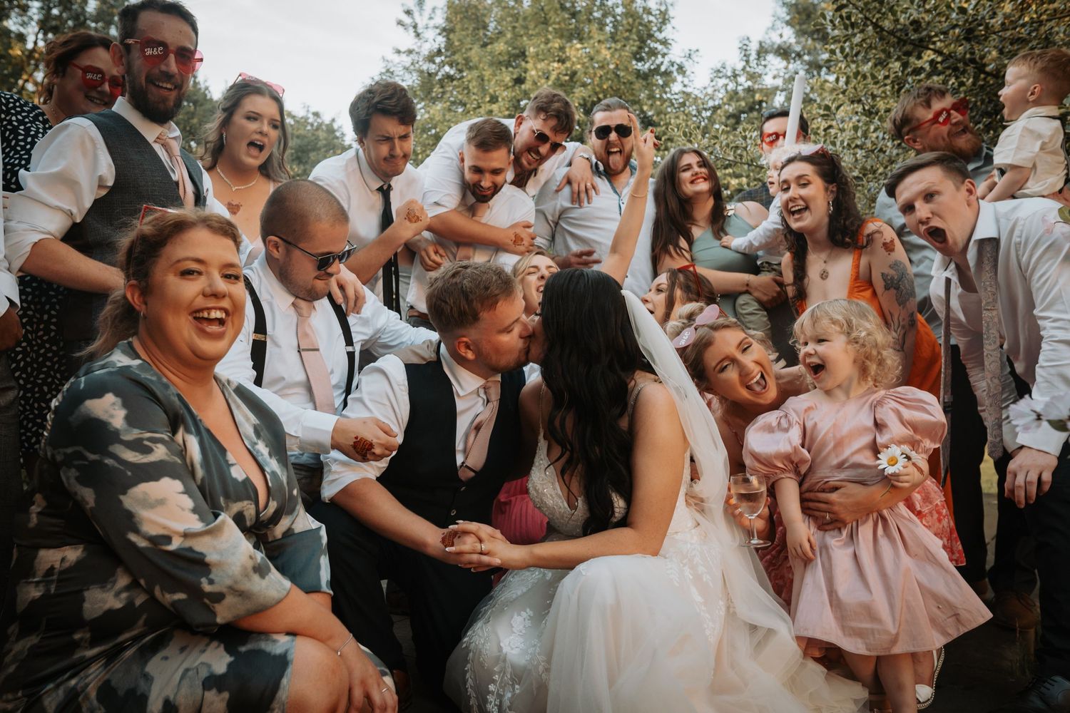 Wedding party dancing and laughing together during outdoor reception celebration with joyful expressions.