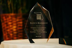 Crystal award trophy with engraved text displayed on white tablecloth.