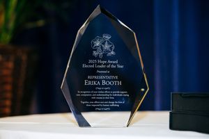 Crystal award trophy displayed against a blue background with engraved text honoring recipient Erika Booth.