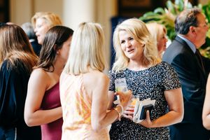 Guests mingle at an elegant indoor reception holding drinks and engaged in conversation.