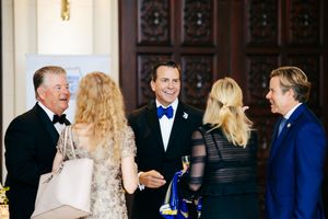 Group of formally dressed people engaged in conversation at an elegant reception.
