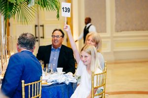 Elegant banquet hall setup with gold chairs and palm decorations for a formal gathering.