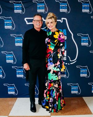 Step and repeat photo with Florida outline backdrop featuring two attendees at formal event.