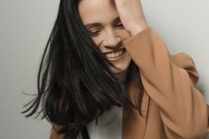 Candid portrait of person in tan blazer laughing with natural movement.