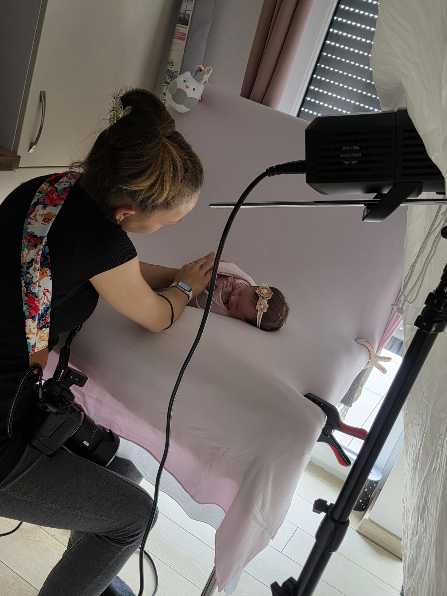 Behind-the-scenes view of professional photographer setting up newborn photo session equipment.