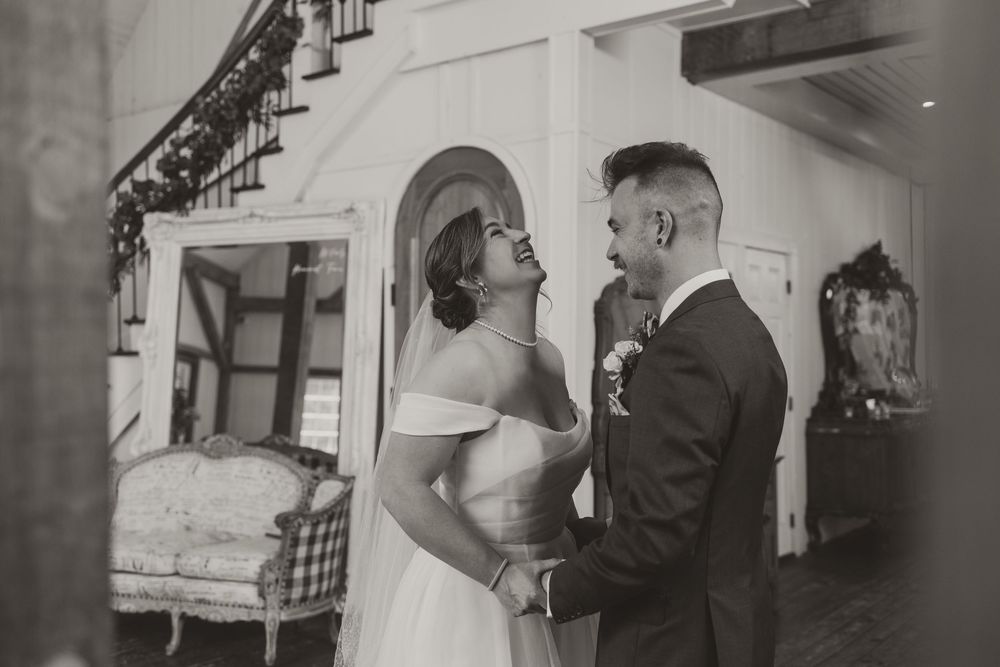 Bride and groom sharing a joyful moment together in elegant black and white wedding portrait.