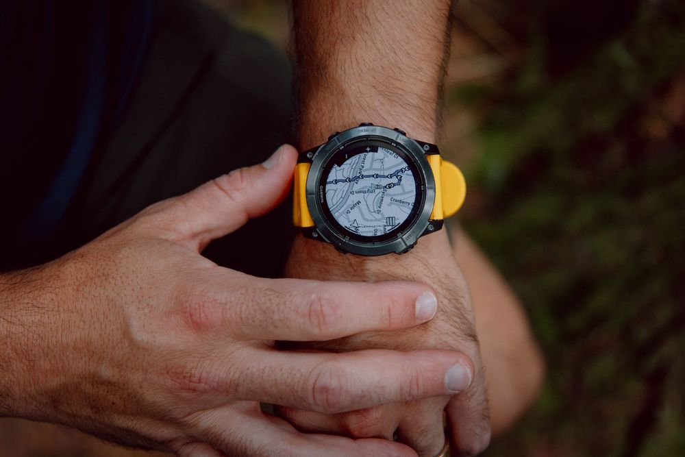 Close-up shots of hands adjusting the time on an orange and black sports watch in sequence.