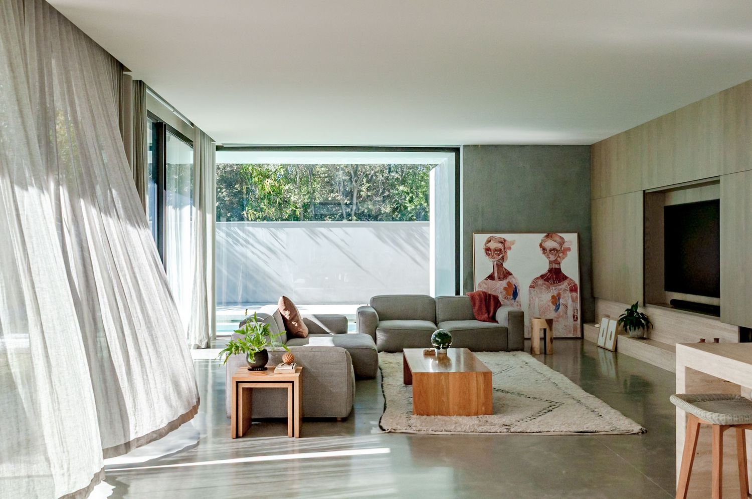 Modern living room interior with panoramic windows, sheer white curtains, and sleek furniture in neutral tones.