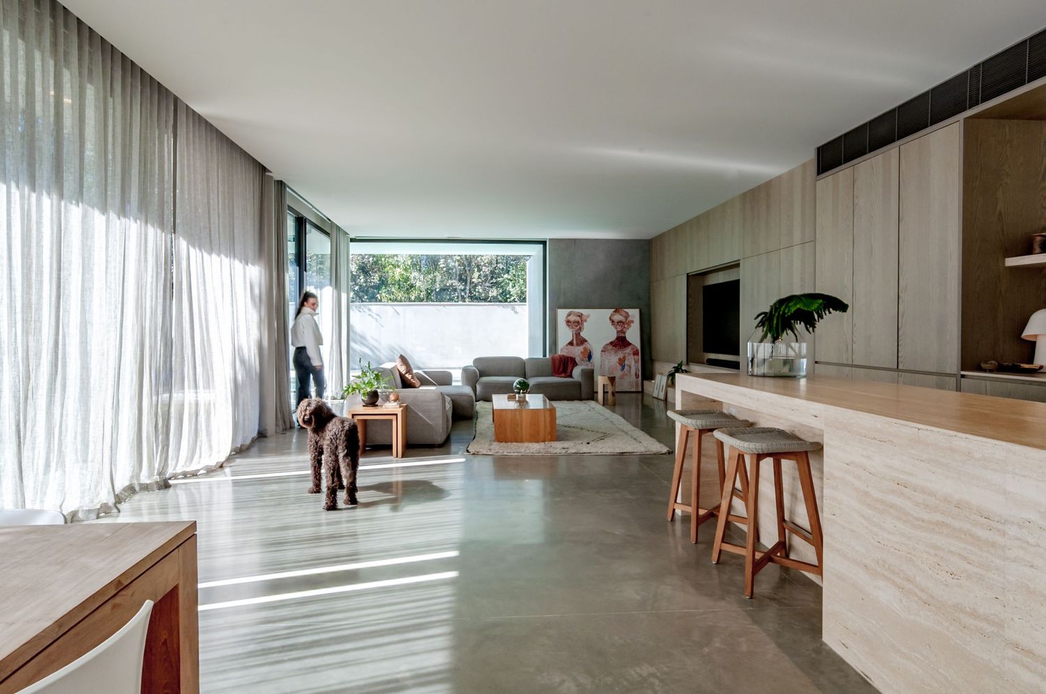 Modern interior of minimalist living room with white walls, wooden floors and built-in storage solutions under natural light.