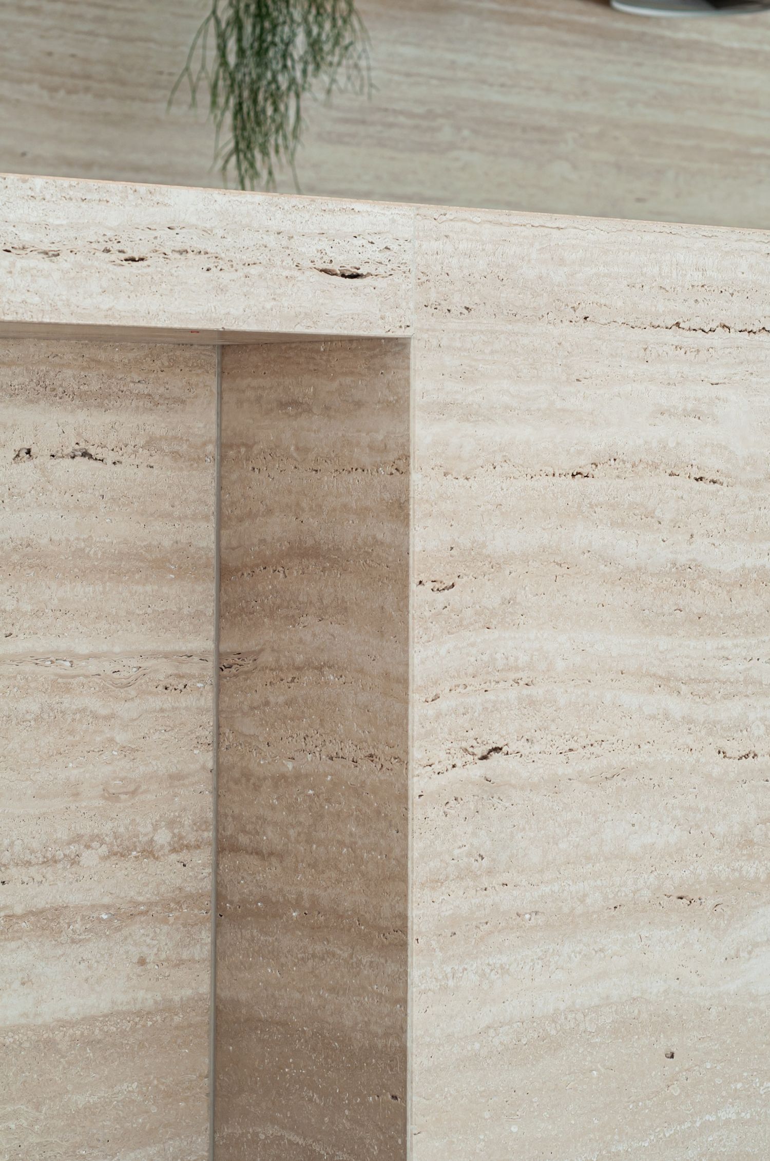 Close-up detail of beige travertine stone tile with natural vein patterns and textured surface showing corner installation.
