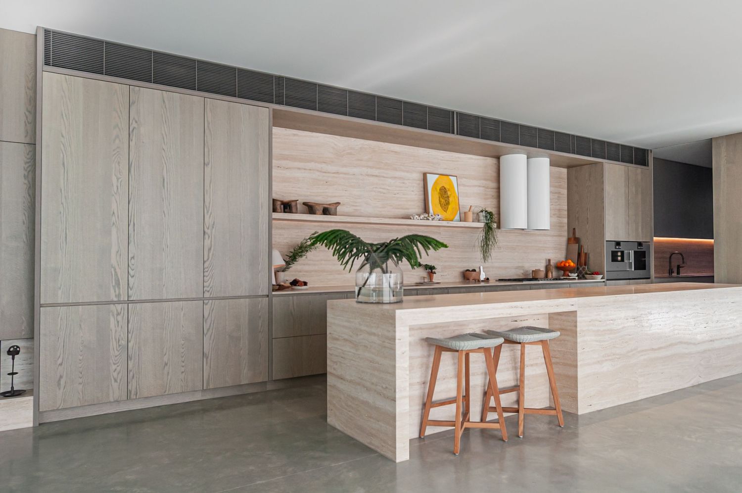 Modern minimalist kitchen with light wood cabinetry, concrete floors, and floating shelves in a natural color palette.
