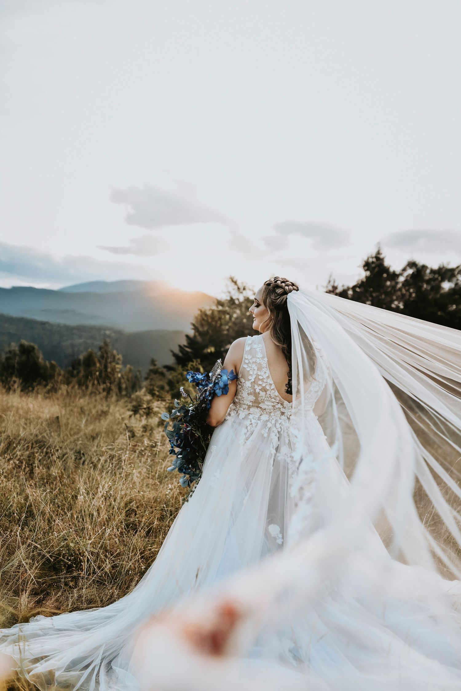 Bride in cathedral veil with delicate floral embroidery captured in Corinth, Texas field.