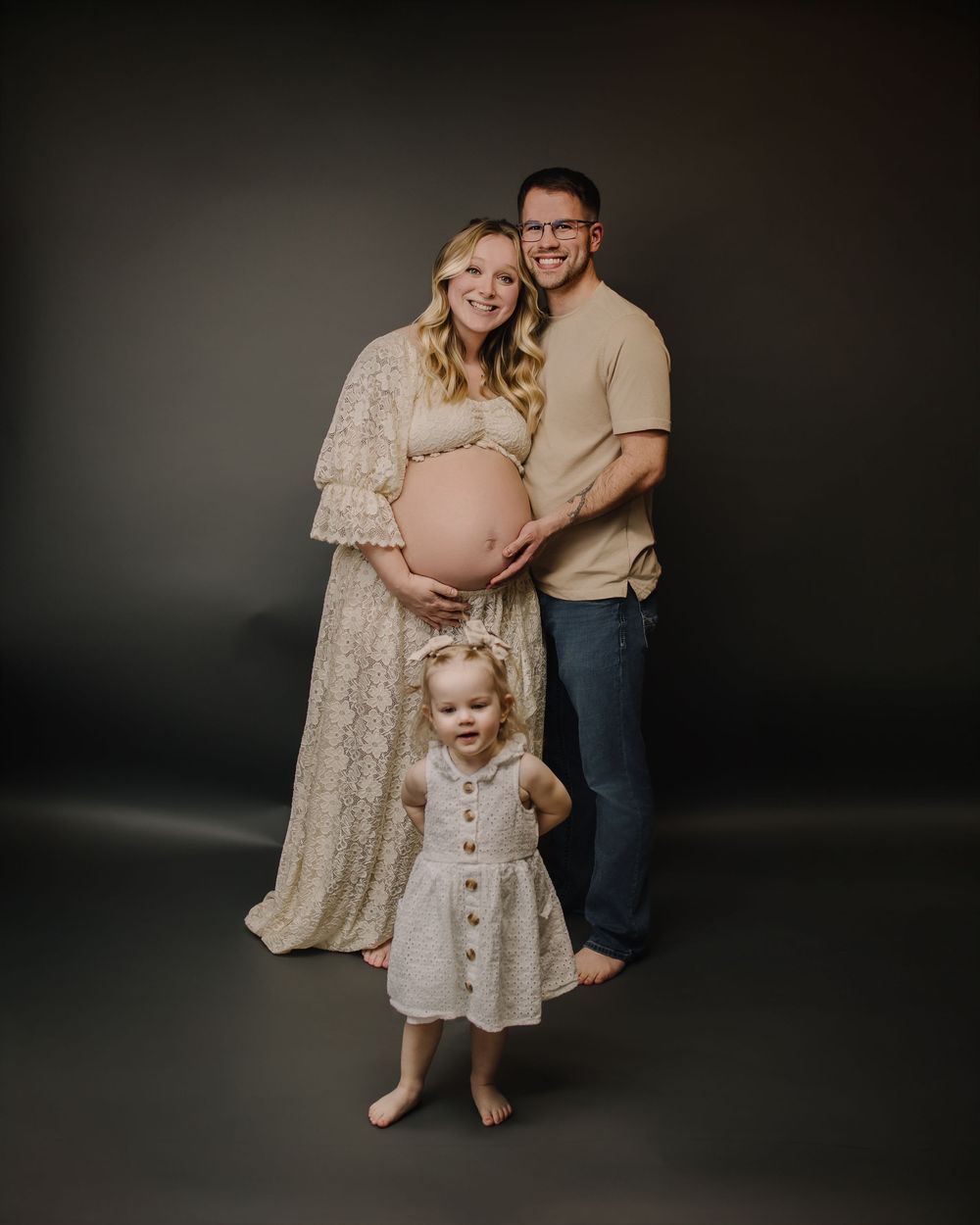 A series of maternity and family photo portraits taken in a dark studio setting against a black background.