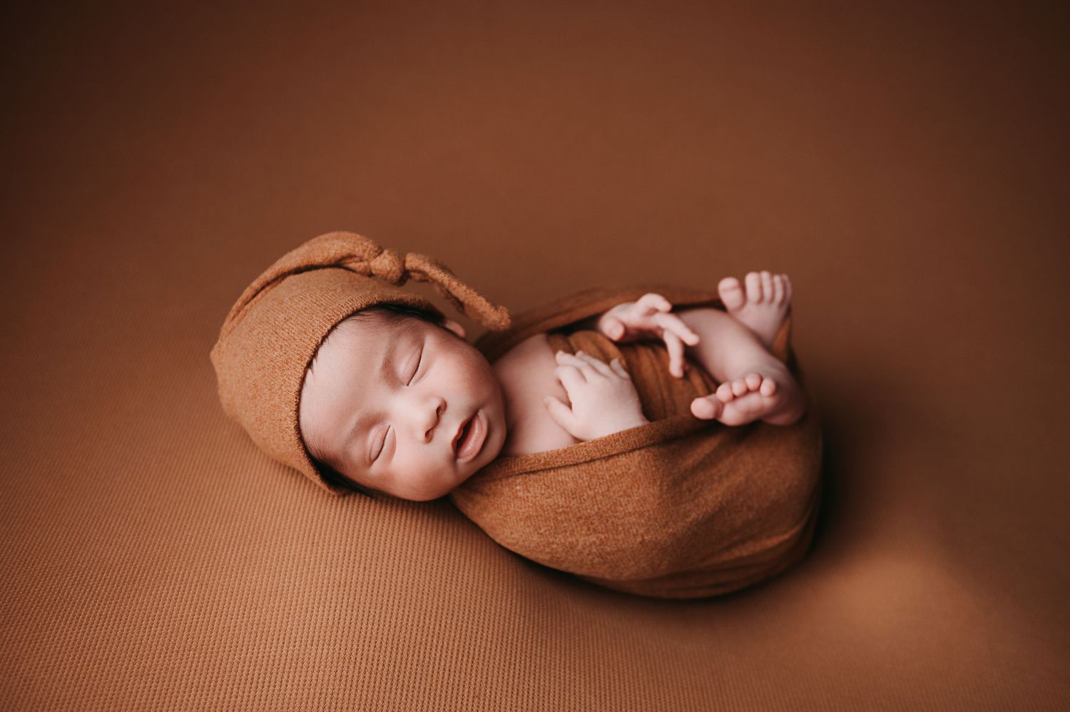 A series of brown toned artistic newborn baby photos showing peaceful sleeping poses on dark backgrounds.