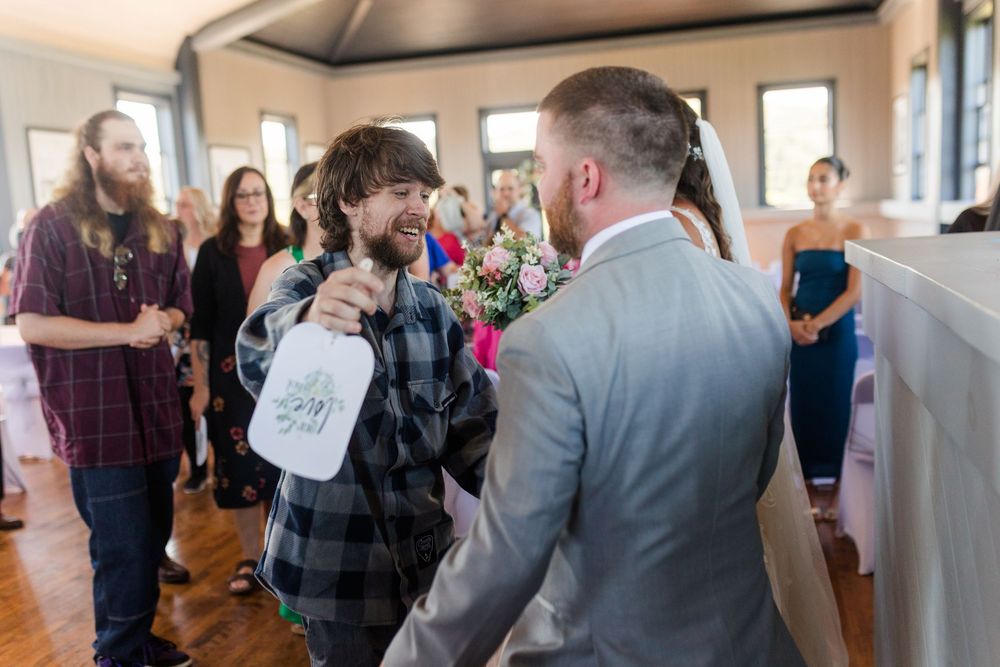 Wedding guests mingle and socialize during a casual reception in a bright indoor venue.