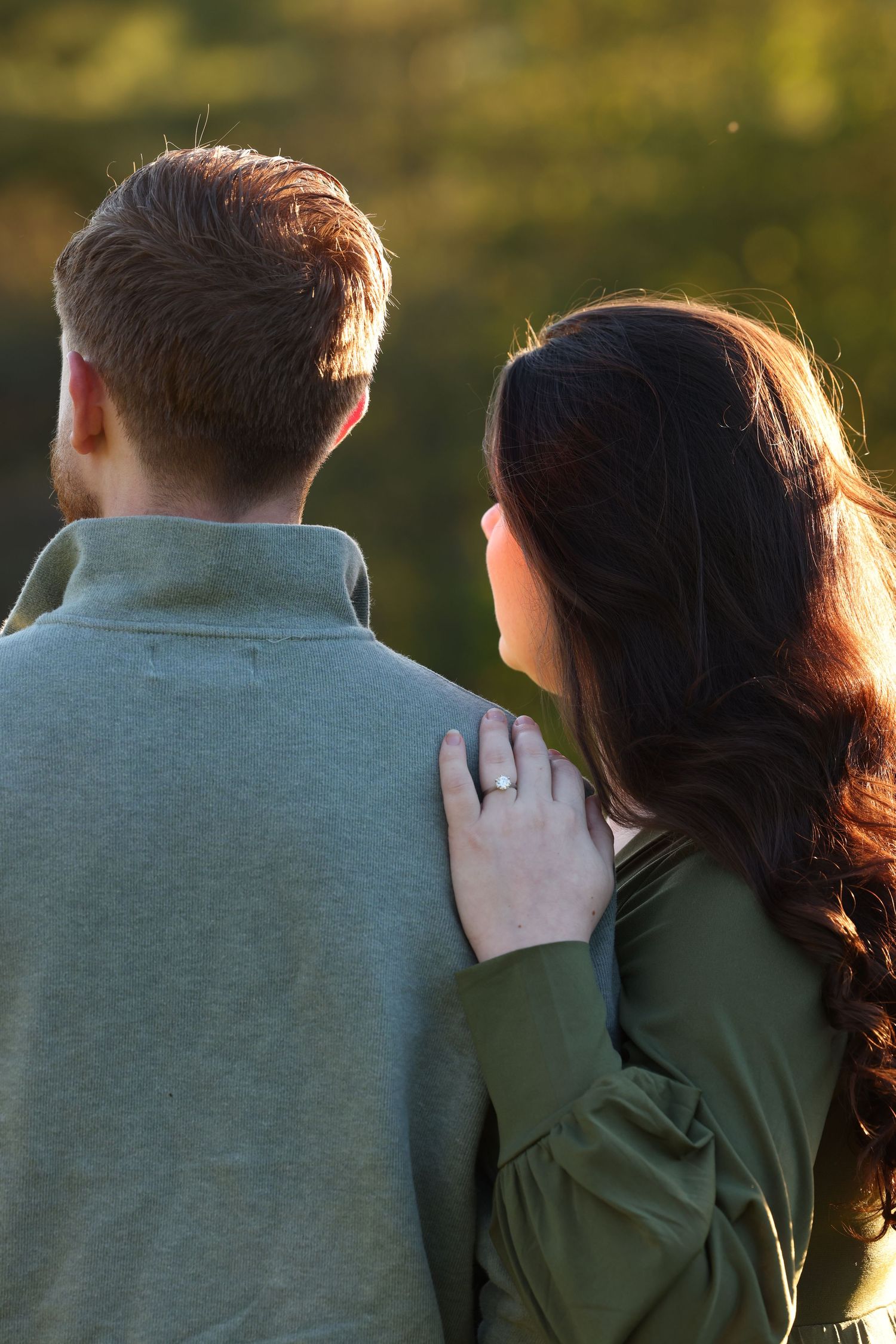 Couple standing together from behind at golden hour outdoors.