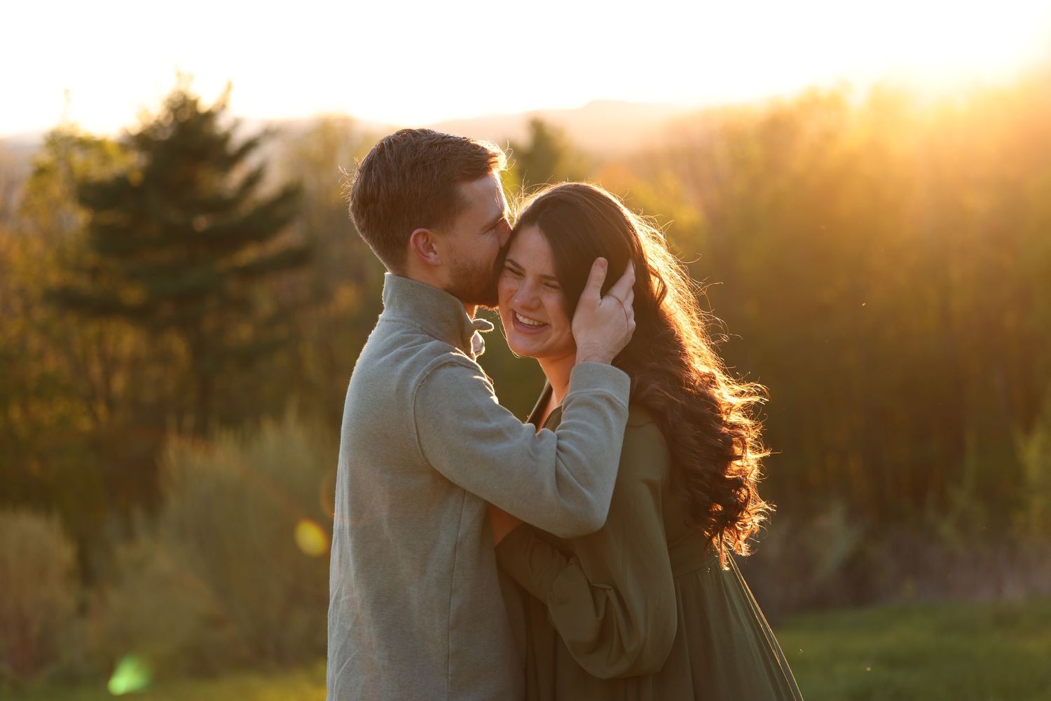 Couple embracing tenderly at golden sunset in outdoor setting.