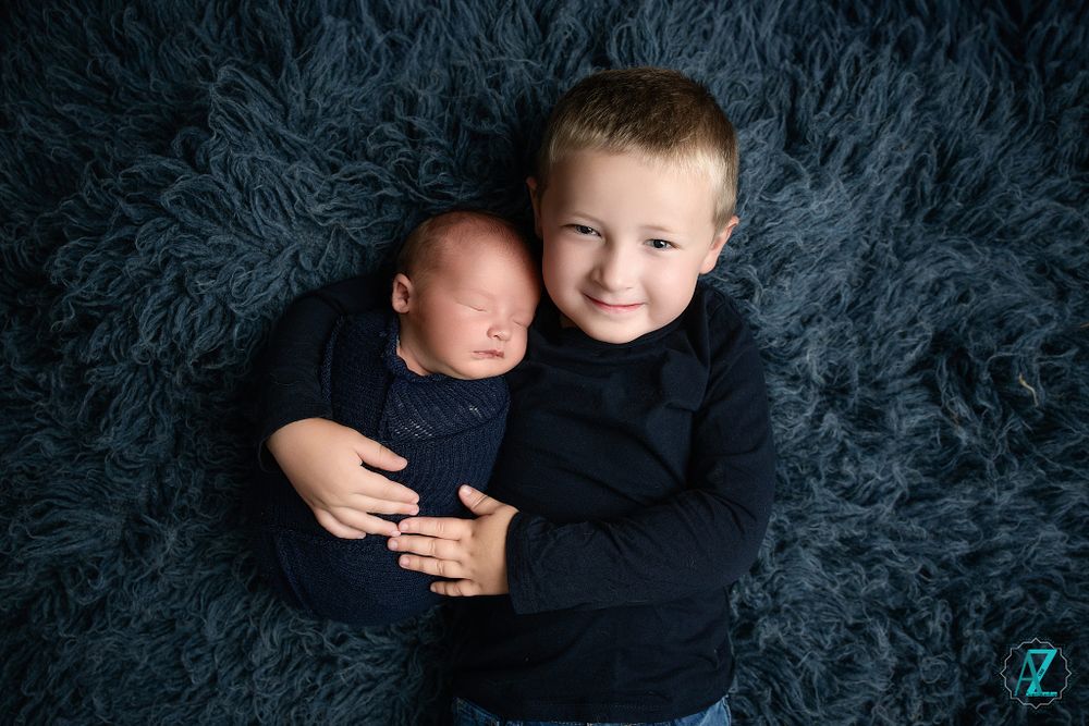 Sweet sibling portrait on gray textured rug showing brotherly affection.