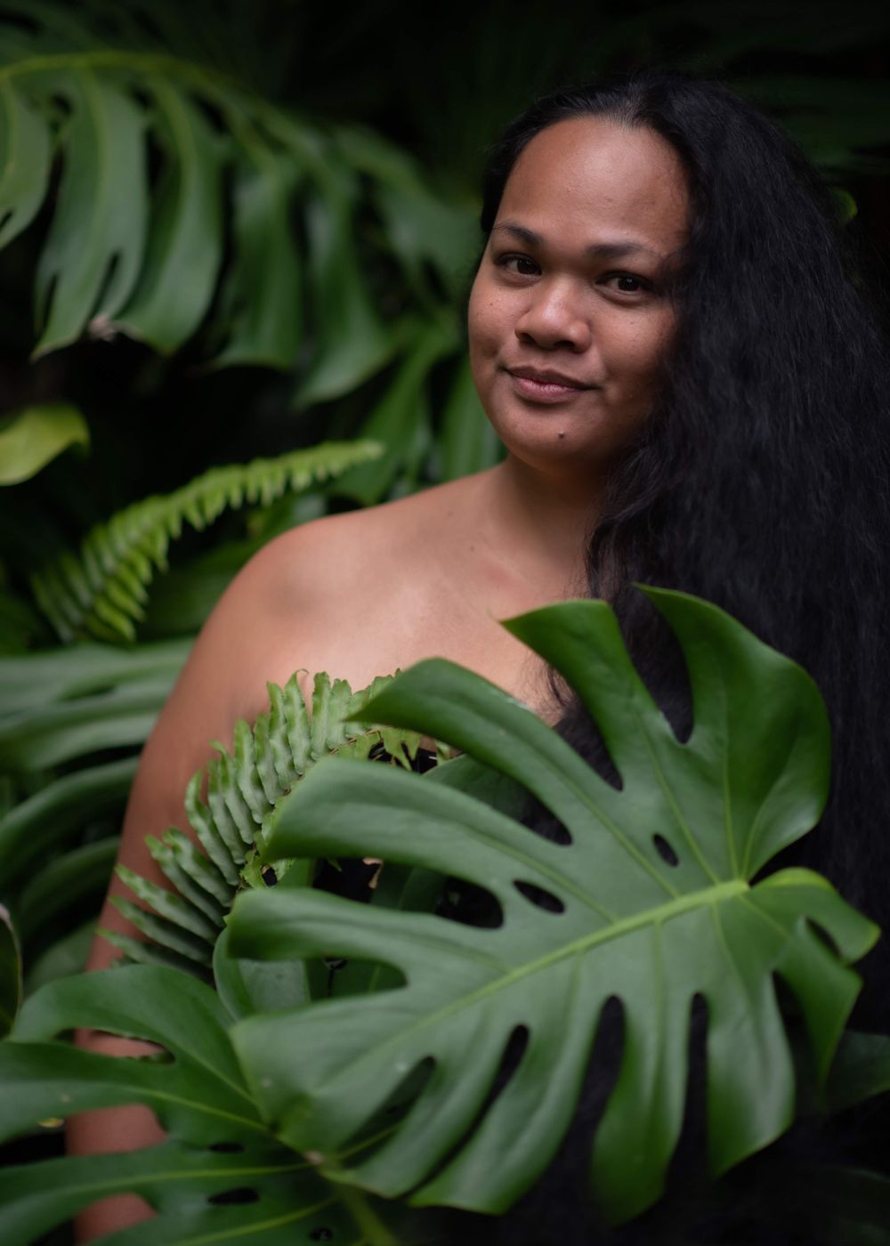 Portrait among lush monstera leaves in tropical setting.