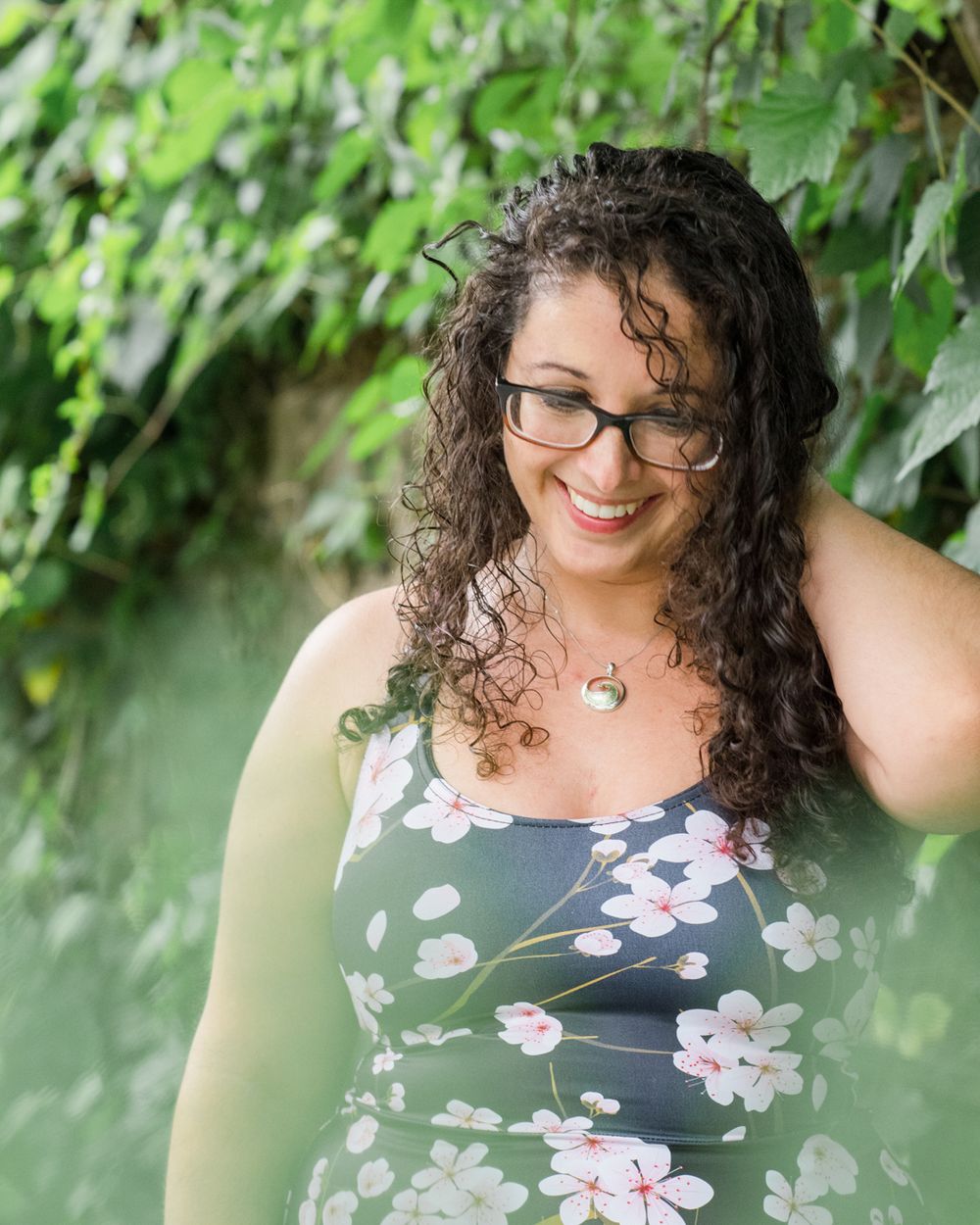 Portrait in floral dress against green leafy background.