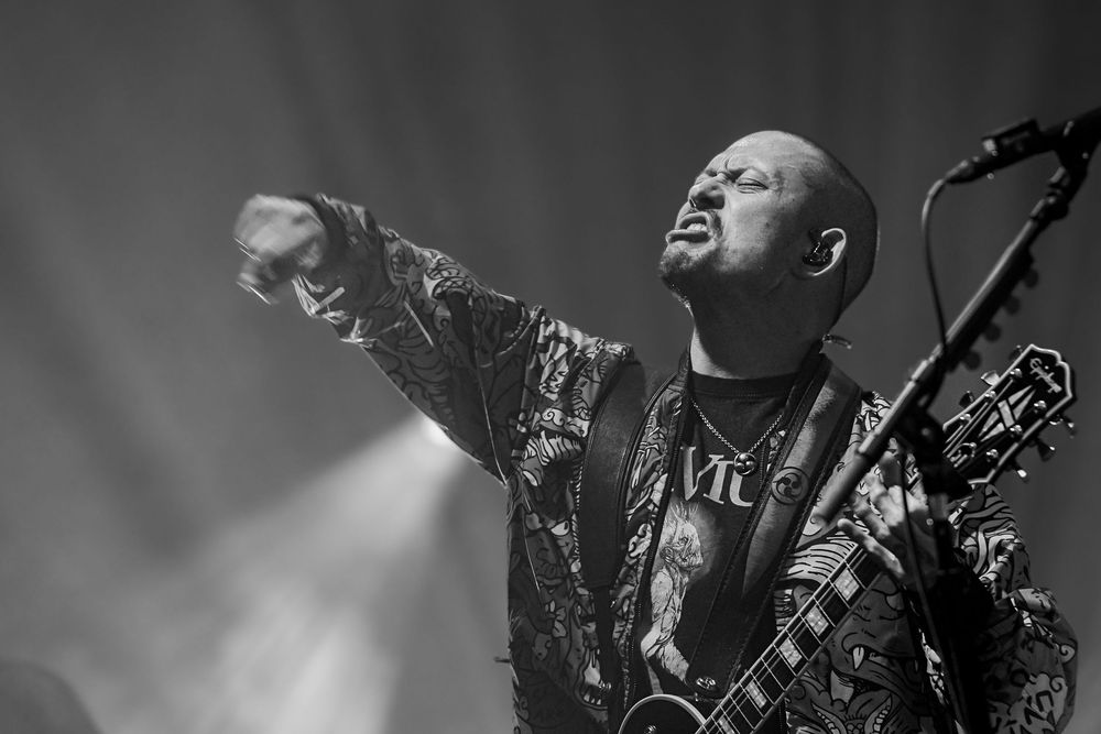 Heavy metal guitarist performs on stage with electric guitar in dramatic lighting during live concert performance.