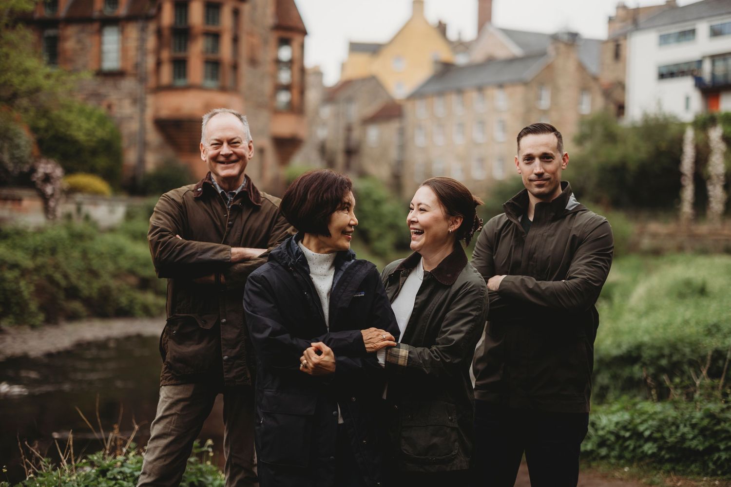 Wedding party laughs together while walking through a garden setting in natural candid moments.