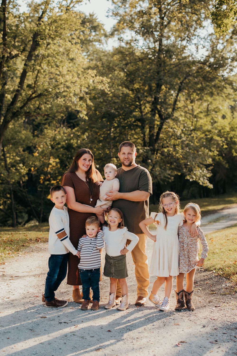 Candid family moment captured on a nature trail with beautiful autumn trees in the background.