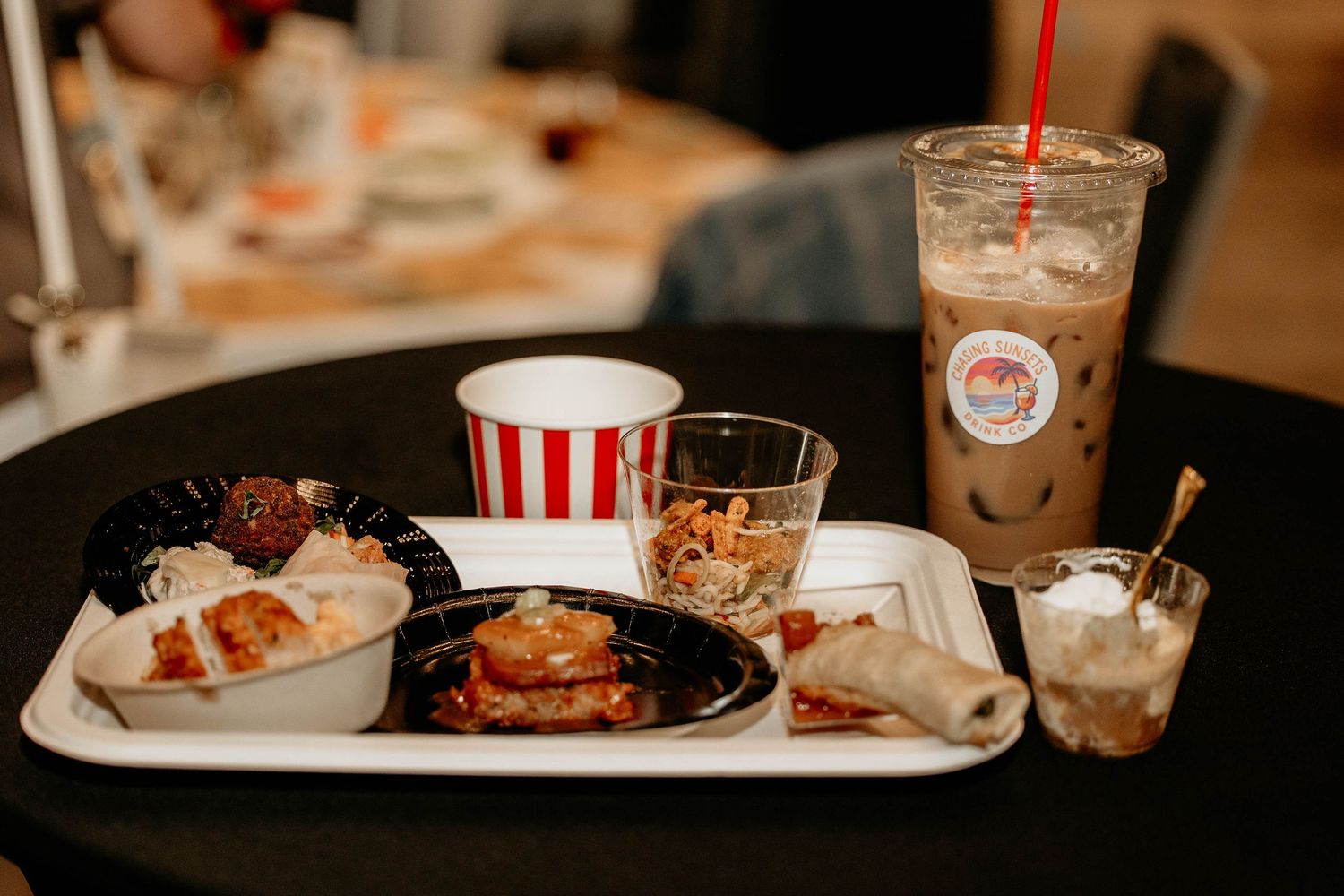 A series of fast food meals and drinks arranged on a table showing burgers, fries, and beverages in a restaurant setting.