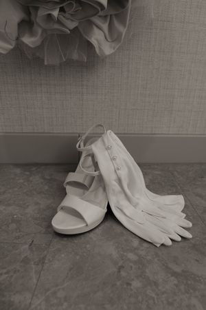 White bridal shoes and gloves arranged on a grey floor.