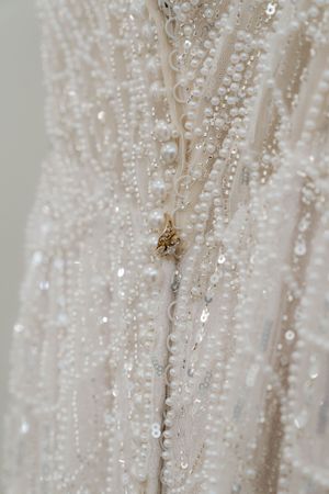 Intricate beadwork and sequins shimmer on white wedding dress material.