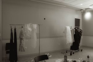 Wedding dresses hanging on display racks in a minimalist white dressing room.