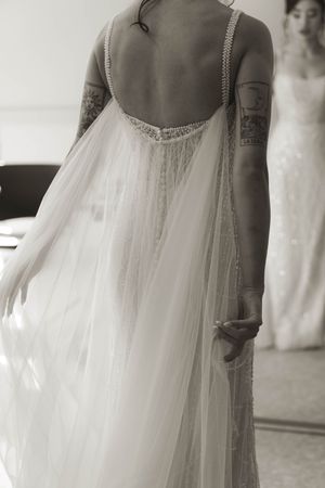 Back view of a wedding dress showing delicate lace details and flowing tulle fabric.