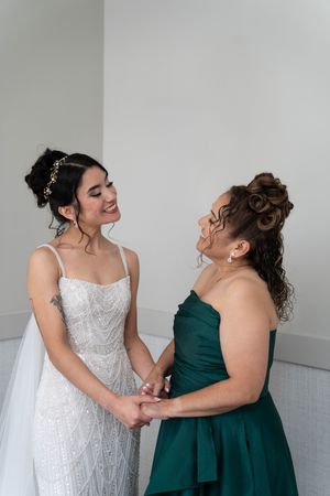Candid moment between two people in formal attire laughing together against a white wall.