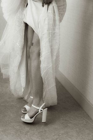 Detail shot of white peep-toe wedding shoes beneath layers of tulle and lace.