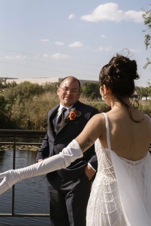 Wedding couple shares a playful moment on a wooden deck by the water.