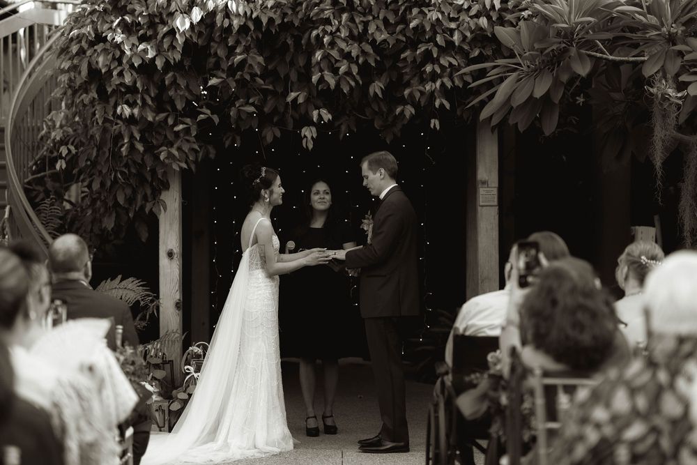 Wedding ceremony moments captured in a garden setting with natural greenery overhead.