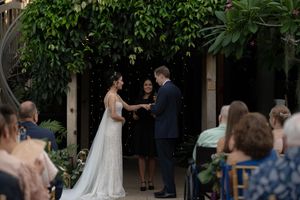 Outdoor wedding venue decorated with lush greenery and white chairs for guests.