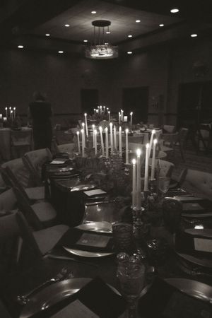Long formal dining table set with multiple white taper candles creating an intimate atmosphere.