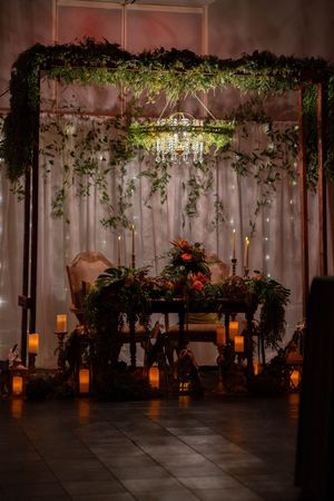 Romantic wedding sweetheart table setup with hanging greenery, fairy lights and lanterns.
