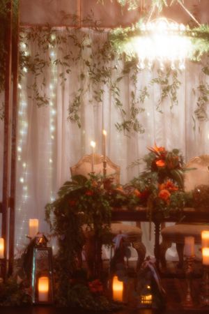 Wedding reception table with cascading greenery, candles and soft lighting creating romantic ambiance.