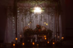 Dreamy wedding reception setup with backlit curtains, hanging lights and candle glow.