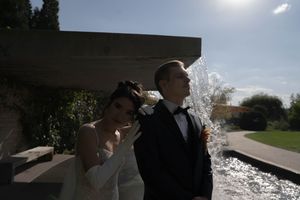A wedding couple shares an intimate moment in a garden setting with dramatic lighting and shadows.